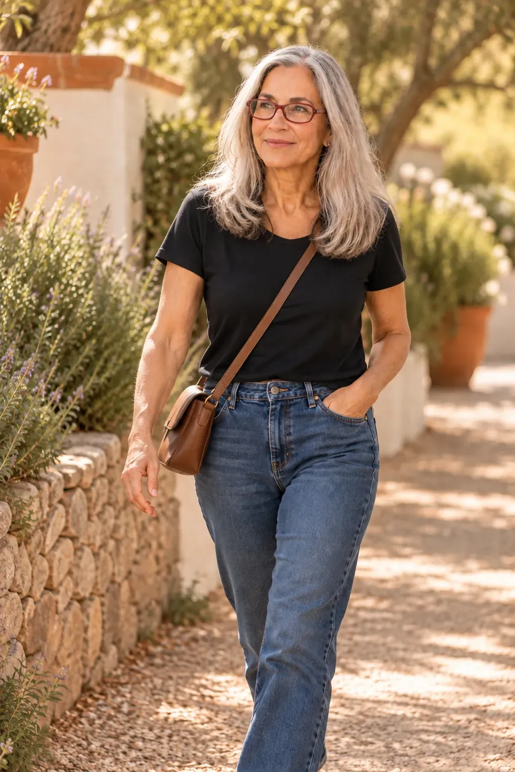 Caren Glasser walking mid-stride along a sunlit garden path in jeans and a black t-shirt, looking ahead with a quiet, proud expression
